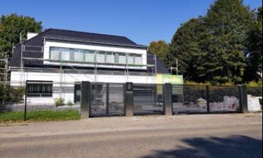 Strakke vleugelpoort bestaande uit stalen horizontale lammellen en RVS palen