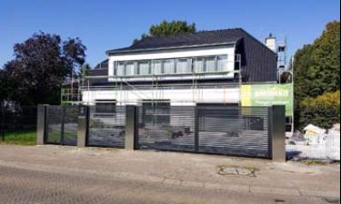 Strakke vleugelpoort bestaande uit stalen horizontale lammellen en RVS palen